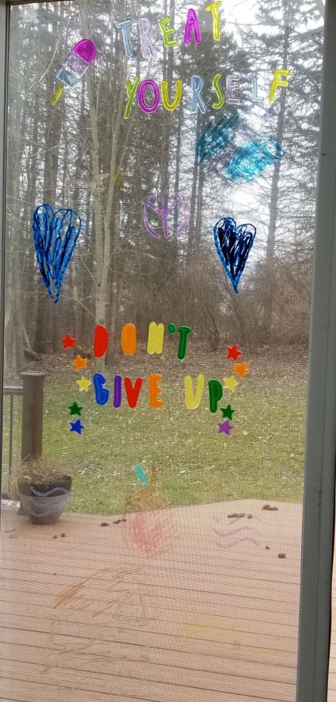 picture of window that has art that says treat yourself and do not give up
